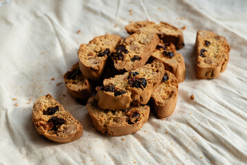 Italian cantuccini biscotti with nuts and dried fruits served on a white linen cloth with scattered ingredients