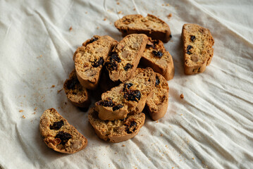 Italian cantuccini biscotti with nuts and dried fruits served on a white linen cloth with scattered ingredients