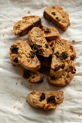 Italian cantuccini biscotti with hazelnuts and cranberries served on a white linen cloth with scattered ingredients