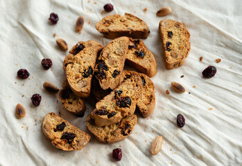 Italian cantuccini biscotti with nuts and dried fruits served on a white linen cloth with scattered ingredients
