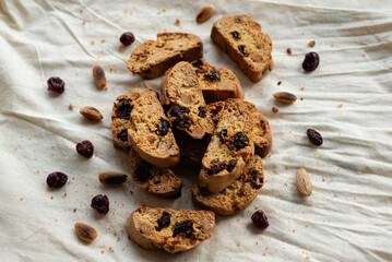 Italian cantuccini biscotti with nuts and dried fruits served on a white linen cloth with scattered ingredients