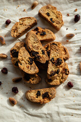 Italian cantuccini biscotti with hazelnuts and cranberries served on a white linen cloth with scattered ingredients