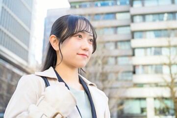 スーツを着てビル街に立つ20代フレッシャーズのビジネスウーマン