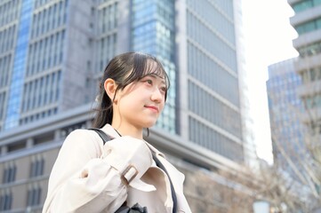 スーツを着てビル街に立つ20代フレッシャーズのビジネスウーマン