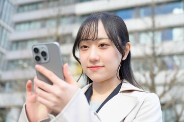 ビル街でスマホを使用する日本人ビジネスウーマン