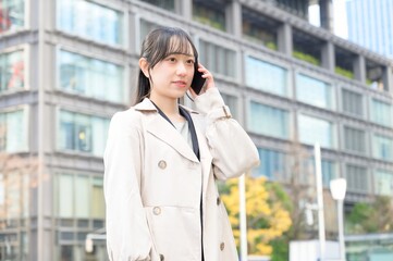 ビル街でスマホを使用する日本人ビジネスウーマン