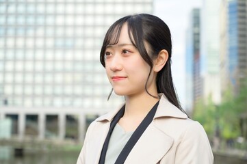 スーツを着てビル街に立つ20代フレッシャーズのビジネスウーマン