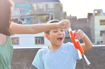 Happy latin siblings holding fruit ice.