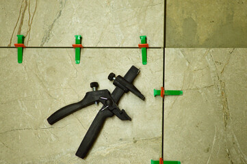 With precise movements, the worker sets the tile in place over the adhesive, securing it with the lash system's wedges to guarantee an even and professional finish.