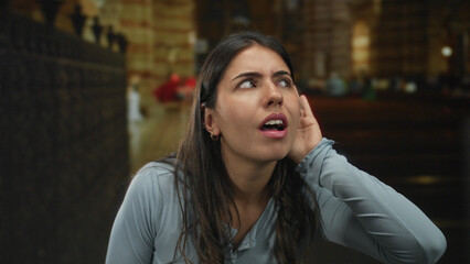 Young woman listening intently in a church setting, conveying curiosity and engagement in the ornate, indoor architectural environment.