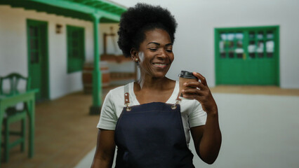 Woman smiling in apron enjoys coffee on city street, embodying urban cafe culture with vibrant positivity in outdoor setting.