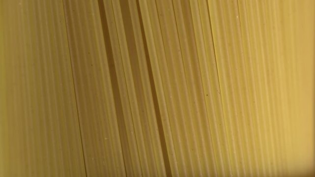 Dry spaghetti pasta background. Macro close-up of uncooked spaghetti strands in parallel lines, minimal abstract texture. Italian food ingredient concept with copy space for cooking and recipes.