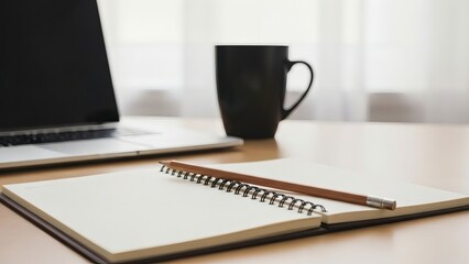 Open notebook and pencil on desk next to laptop and coffee mug, ready for work.