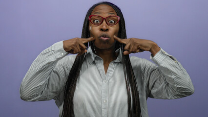 Woman making playful faces against a vibrant purple backdrop, wearing glasses and a striped shirt, showcasing humor and expressive personality.