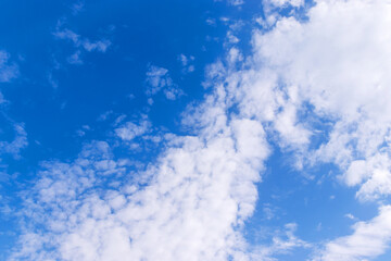Bright blue sky with white fluffy clouds on sunny summer day