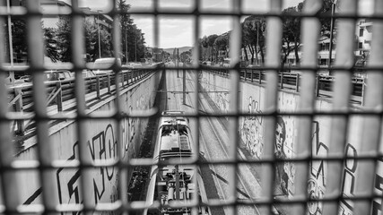 Tram passing under a bridge in an urban cityscape during daytime
