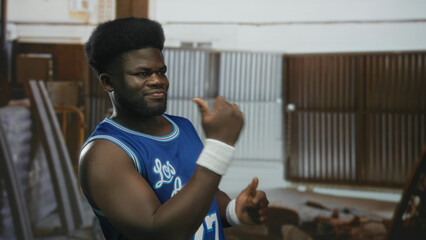 Young man in blue basketball jersey pinches nose, gives thumbs up and points with wristband in...