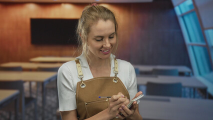 Woman writing notes in classroom setting with blonde hair wearing apron, conveying educational scene with focus on learning and instruction indoors.