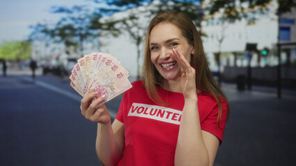 Woman holds fan of turkish lira banknotes and cups hand by mouth on street; charity generosity...