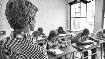 Teacher checking students doing school tests in a teenager classroom