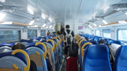Obraz premium Train interior defocused with blue seats, aisle and overhead racks, shallow bokeh atmosphere; background backplate copyspace calm.