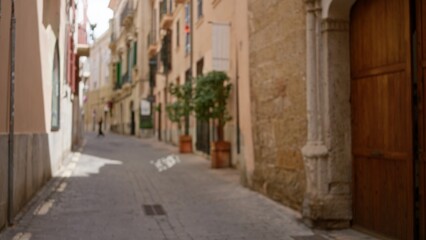 Narrow street in a mediterranean old town with blurred architecture and bokeh effect capturing the charm of urban life in a historical setting.