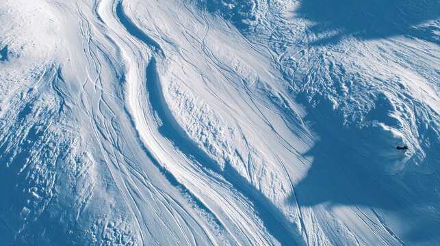 Aerial view of winding ski tracks on a snowy mountain slope, winter landscape