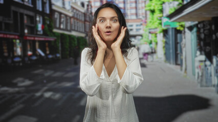 Woman hispanic signing with hands and pursed lips, mouthing and gesturing at camera on a street...