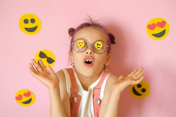 A surprised girl in glasses with emoji icons pasted on the lenses. World Smile Face and Social Media Day