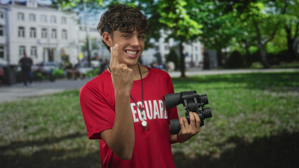 Man lifeguard wearing red tshirt and lanyard holds binoculars and points finger to chest in front...