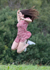 H&uuml;bsche Teenagerin h&uuml;pft und springt in der Natur