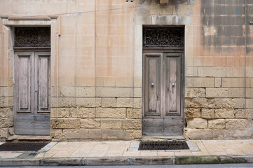 Authentic weathered house facades in Iz-Zeytun with ochre limestone walls, wooden doors and windows reflecting traditional Maltese architecture Iz-Zeytun, Malta, 10 DEC 2025.