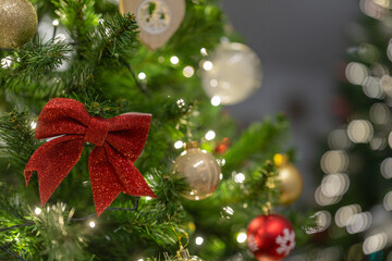 A decorated Christmas tree glows with warm white lights, featuring a red glitter bow and gold ornaments, creating a festive and elegant holiday atmosphere with soft bokeh in the background.