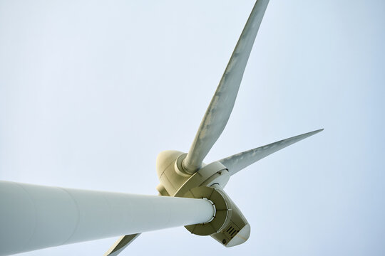 Close up of wind turbine with three blades against clear sky, viewed from below. Wind turbine against clear sky.
