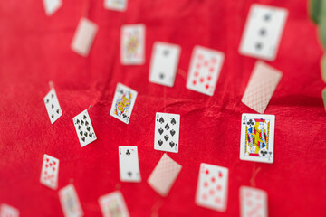 Close-up view of scattered playing cards, varying designs on top right corner, red background.