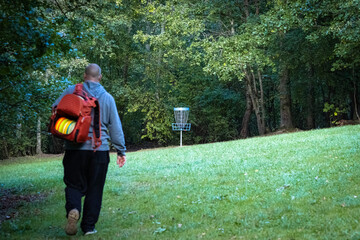 discgolfer is walking towards a basket