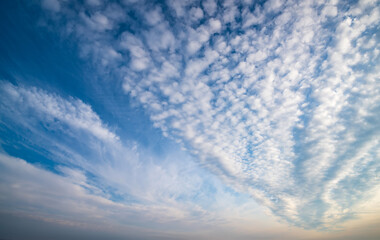 Blue daytime sky filled with delicate white cirrus clouds forming feathery, textured patterns across the frame, evoking serene openness and airy vastness of atmosphere