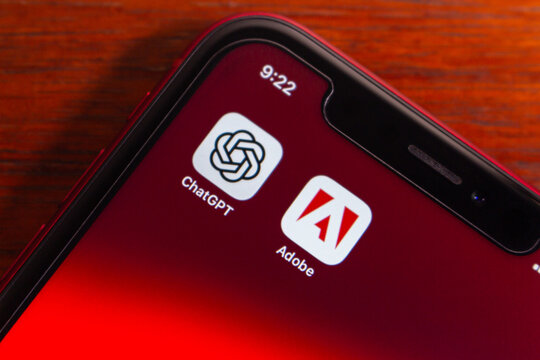 Quito, ECUADOR - Dec 15 2025 : Close-up of a smartphone screen showing the ChatGPT and Adobe icons, symbolizing AI, design, graphic and documents workflow integration.