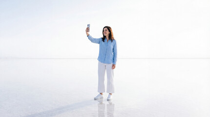 Woman taking a selfie with her smartphone in a minimal white landscape