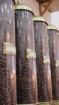 Various roasted coffee beans types in decorative glass tubes on wooden stand on street market in Jerusalem. Different varieties of coffee in flasks. Vertical video