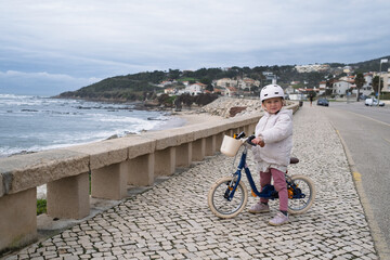 Fototapeta premium Little girl riding a two wheeled bicycle wearing a helmet