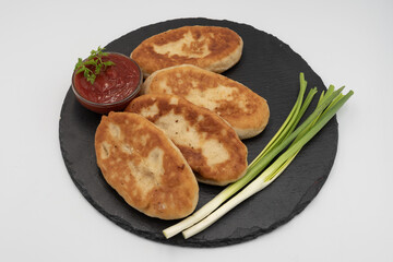 Homemade fried potato pies served with tomato sauce and fresh herbs on black slate plate