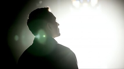 Silhouette of a man in front of bright light, mysterious and dramatic.