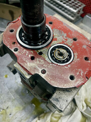 Hydraulic pump engine unit industrial repair metal machinery component with oil leakage on a workshop table for technical maintenance and mechanical engineering service center context