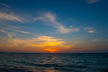 Fototapeta premium Beautiful sunset. Tranquil closeup calm sea water waves with palm trees. Tropical island beach landscape exotic shore coast. Summer vacation, holiday amazing nature, Maldives.