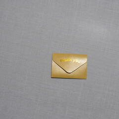 A small  envelope with &ldquo;Thank you&rdquo; embossed on it rests on a soft textured surface, symbolizing gratitude, elegance, simplicity, and thoughtful appreciation in a minimal scene.