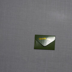 A small  envelope with &ldquo;Thank you&rdquo; embossed on it rests on a soft textured surface, symbolizing gratitude, elegance, simplicity, and thoughtful appreciation in a minimal scene.