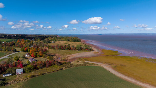 Aerial view over the Minas Basin at Cobequid Bay near Burntcoat Head Park at low tide, revealing autumn landscapes, exposed seabed, and dramatic coastal forms under a clear blue sky.