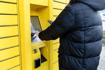 Woman Using Smartphone at Parcel Locker – Contactless Delivery, Online Shopping, Smart Logistics...