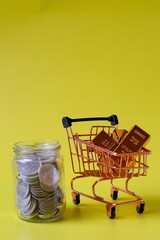 trolley containing gold bars and coins in a jar with a yellow background